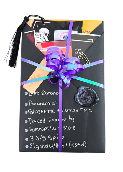 A wrapped gift package or subscription box featuring a black envelope-style wrap with a purple ribbon, a large purple bow, handwritten white text on the front, and assorted tags and inserts visible at the top.